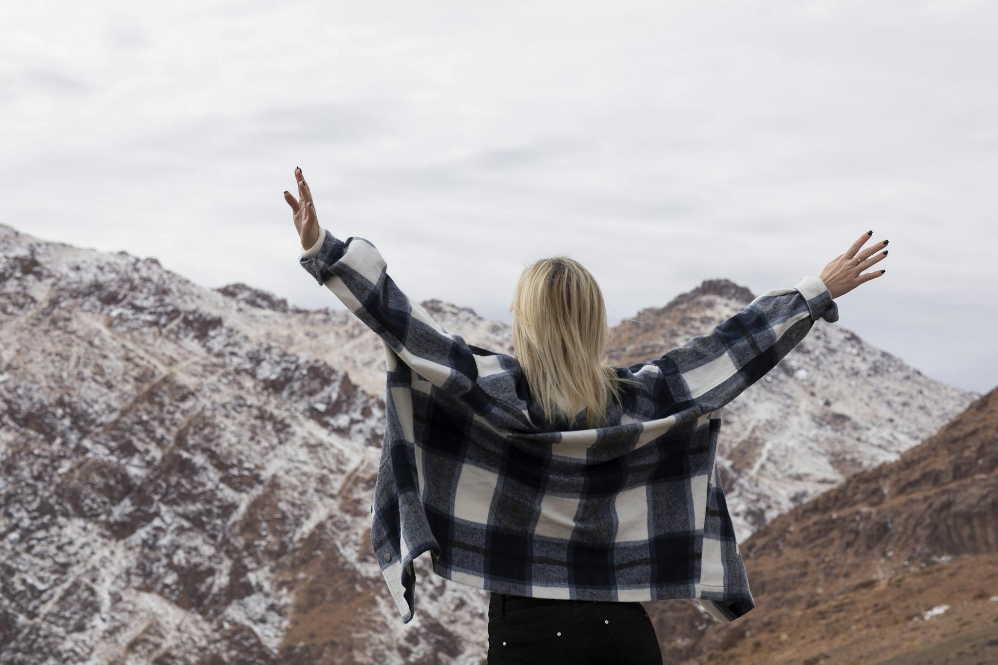 A woman with arms raised in a snowy mountain setting, enjoying a sense of freedom and adventure.