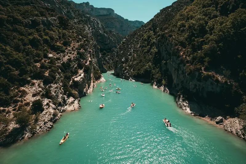 Kayakers paddling through a turquoise river canyon