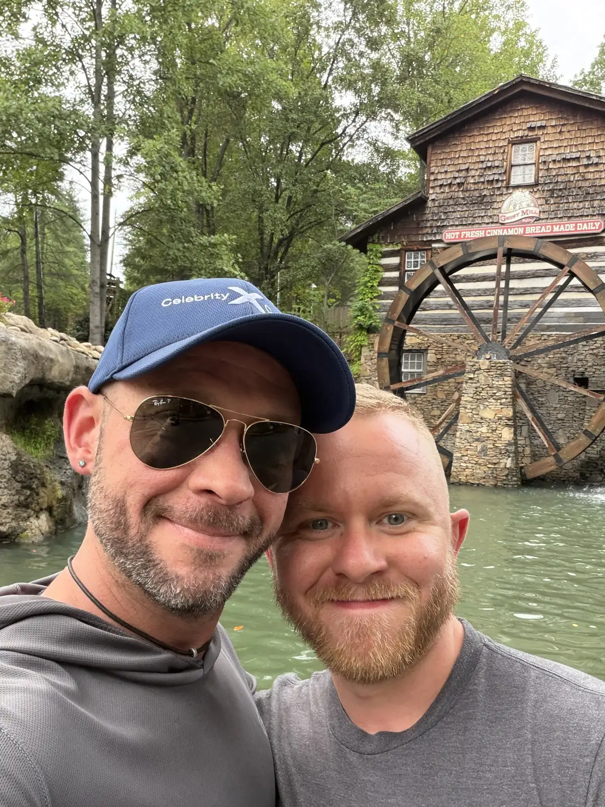 Fox and his husband Brandon taking a selfie in front of the wooden grist mill and water wheel at Dollywood