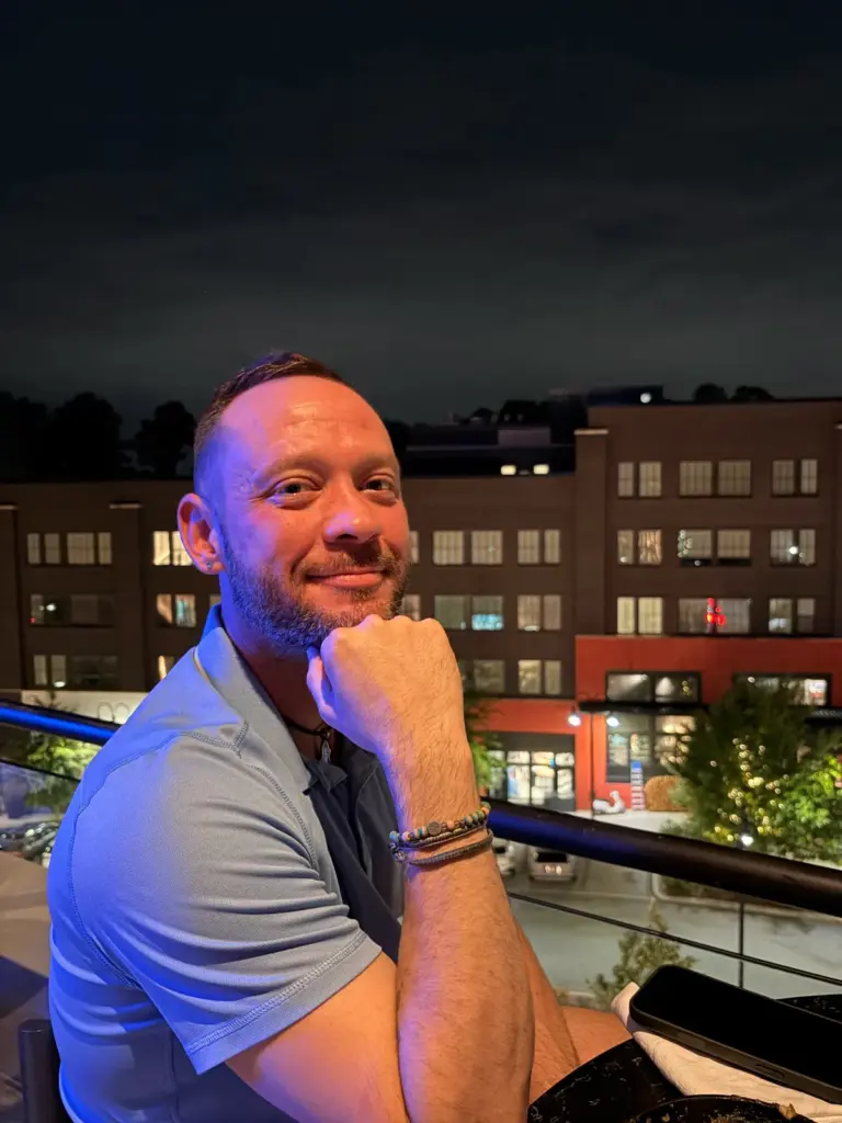 Fox smiling on a rooftop at night with city buildings behind him