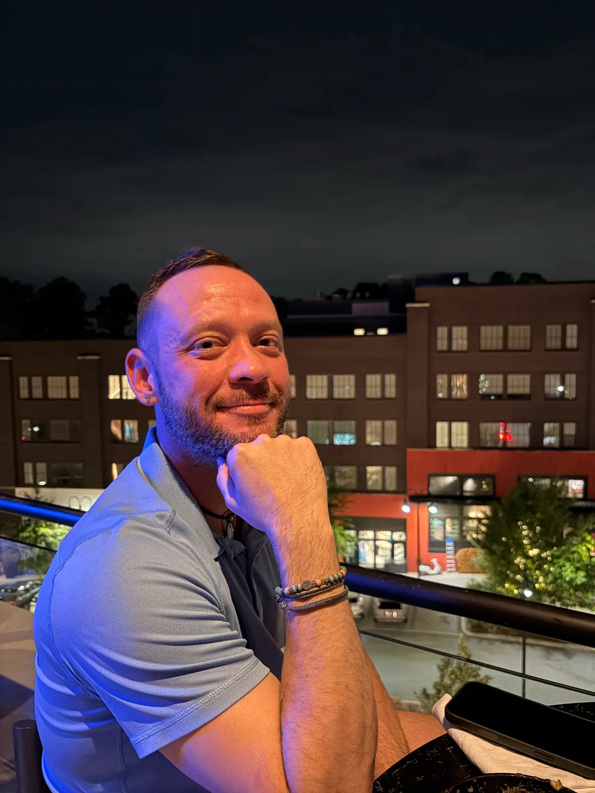 Fox smiling on a rooftop at night with city buildings behind him
