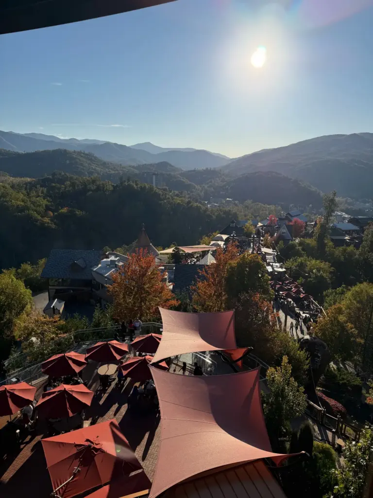 View over a mountain town with red shade sails and fall-colored hills