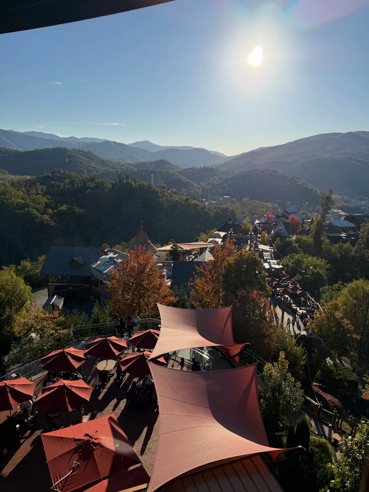 View over a mountain town with red shade sails and fall-colored hills